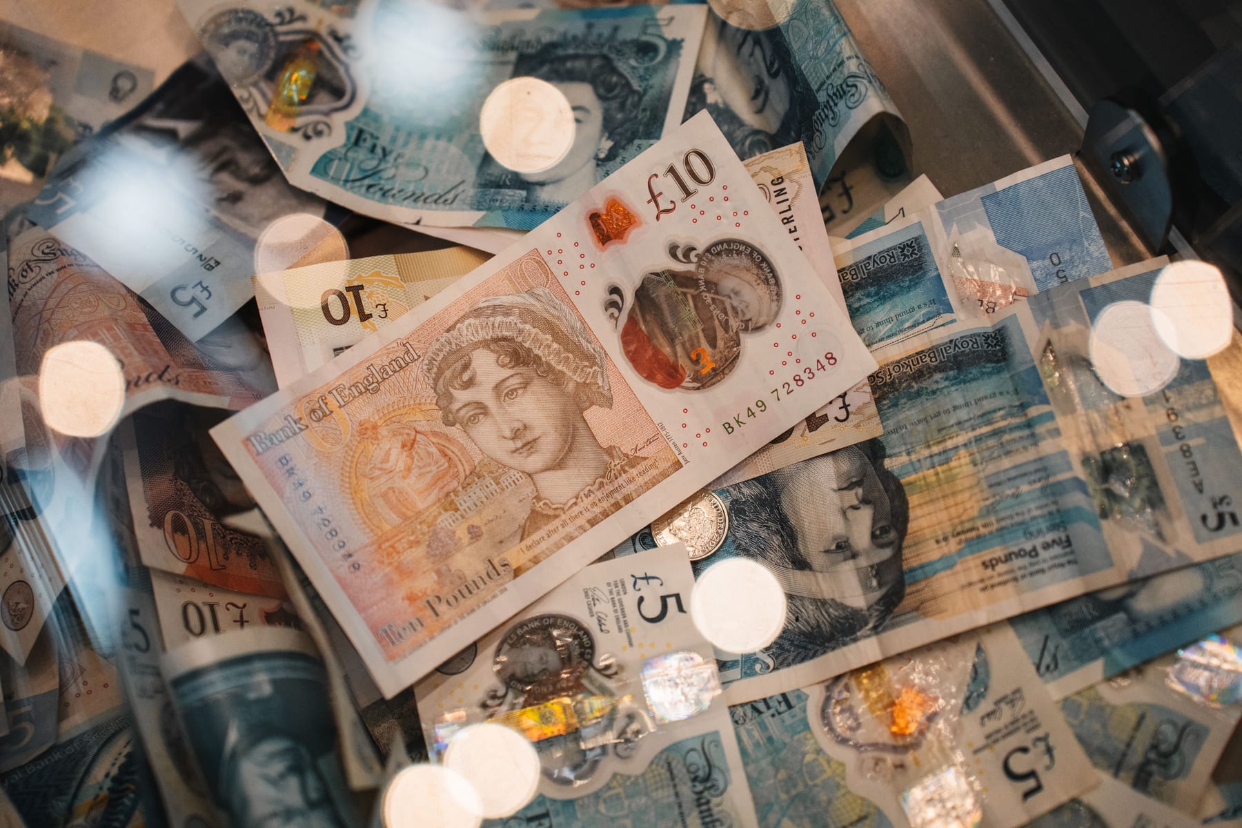 Close-up of British five and ten pound notes with coins and warm bokeh